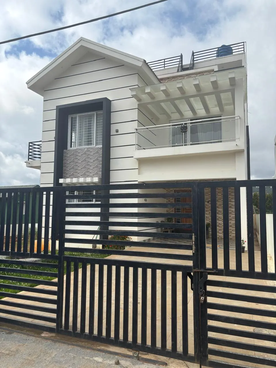 The 4 BHK villa, a white two-storey house behind a black gate